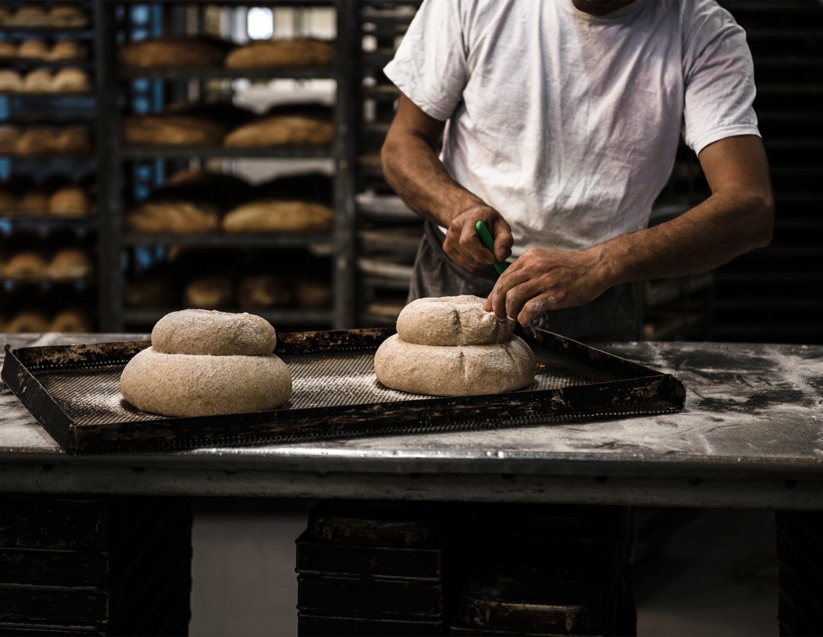 A Cavan baker shaping loaves in front of racks of fresh bread