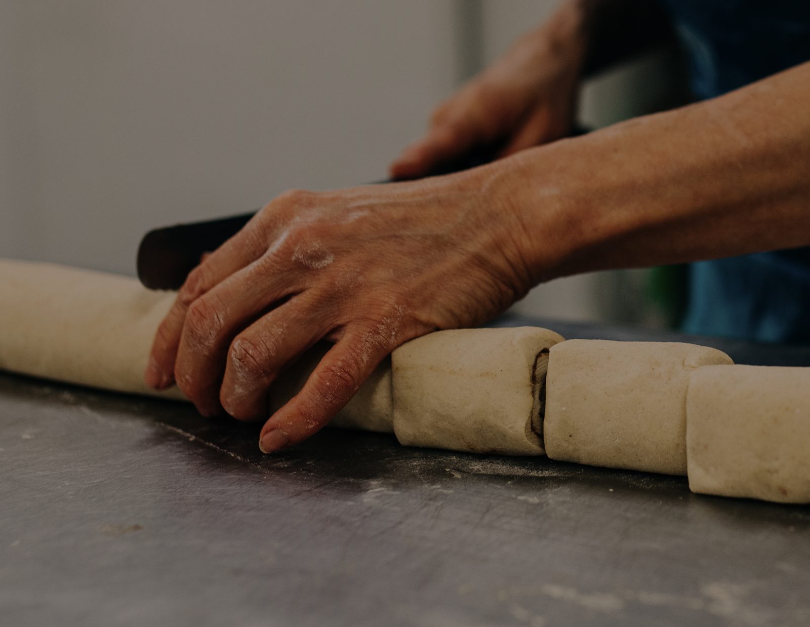 A baker's hands dividing dough on the bench